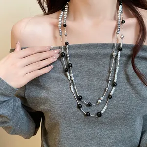 Detail of retro double-strand acrylic pearl necklace worn on model with grey top.