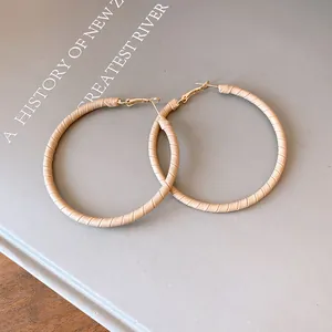 Detailed close-up showing the texture of beige leather wrapped golden hoop earrings