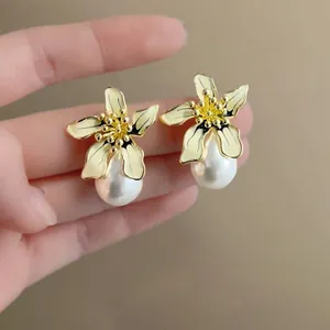 Vista detallada de pendientes de flores bañados en oro vintage con perlas elegantes