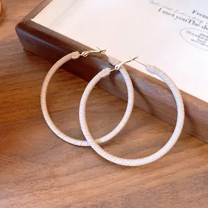 Detailed macro view of beige leather wrapped hoop earrings with gold-tone metal hooks