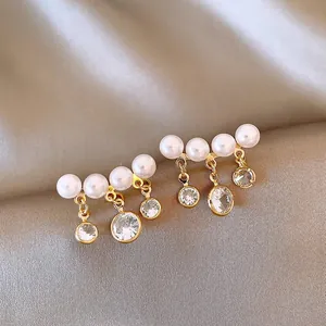 Detalle de pendientes de oro vintage con perlas y circonitas cúbicas redondas brillantes