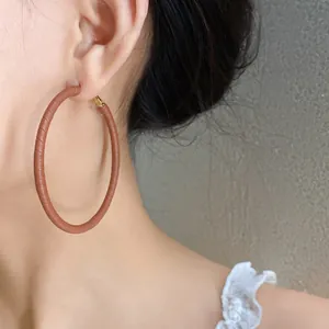 Close-up of brown leather wrapped hoop earrings on model with lace detail