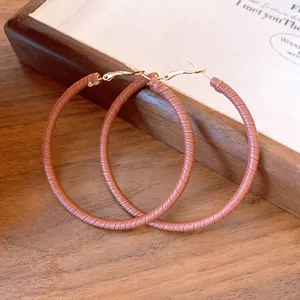 Macro view of brown leather wrapped hoop earrings showing fine texture and metallic hooks