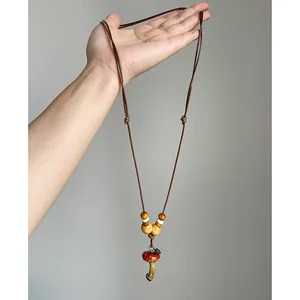 Close-up of a handmade mushroom pendant necklace with wooden beads held in hand.