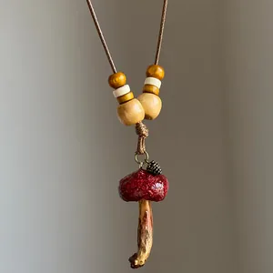 Macro detail of retro ethnic mushroom necklace with wooden beads and pinecone charm