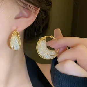Detailed macro view of gold mesh moon boat earrings with sparkling crystals