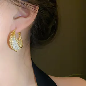 Close-up detail of mesh moon boat shaped gold earring worn by an Asian model for fashion.