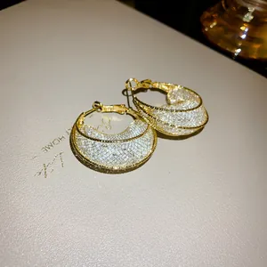 Detailed view of elegant golden mesh moon-shaped hoop earrings featuring sparkling crystals