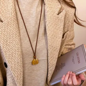 Close-up of a French vintage necklace with a leather cord and a bag-shaped pendant