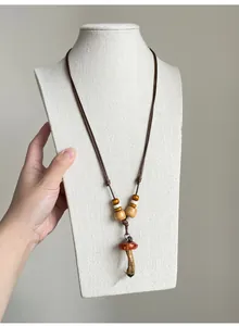 Detail of vintage ethnic style wooden bead necklace with a mushroom pendant on a white display.