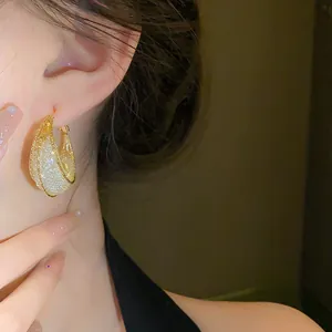 Close-up of elegant gold mesh moon boat earrings with sparkling interior texture
