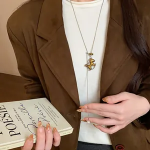 Detailansicht der Halskette mit beflocktem Harzpferd und Perle auf braunem Blazer.