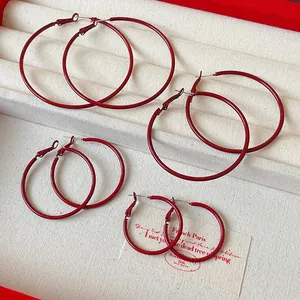 Close-up of Ankara red hoop earrings in four different sizes on a jewelry tray