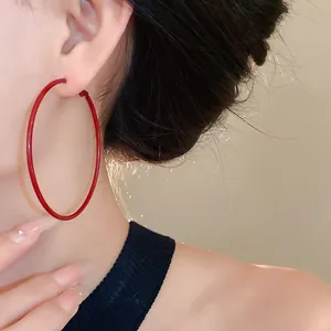 Detail view of large Ancora red minimalist hoop earring on model's ear