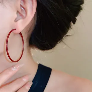 Close-up of a model wearing large ancora red minimalist silver needle hoop earrings