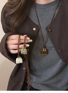 Close-up detail of vintage handbag pendant necklace featuring marble and tiger eye stones