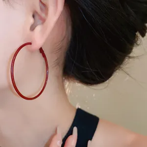 Detail view of large Ancora red minimalist hoop earring on Asian model.
