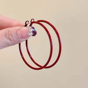 Close-up of elegant dark red hoop earrings with a minimalist circular design and silver needle