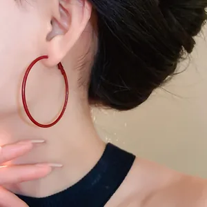 Close-up detail of large Ancora red hoop earrings worn on ear with minimalist design