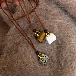 Close-up detail of vintage handbag-shaped stone pendants with brown leather cord