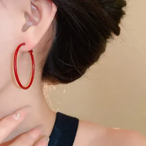 Close-up detail of vibrant red hoop earrings worn by a model