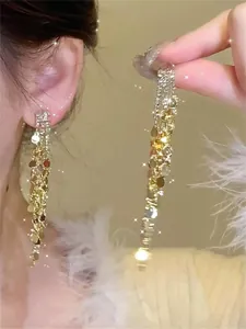 Close-up detail of sparkling gold tassel earrings featuring zircon crystals and sequins