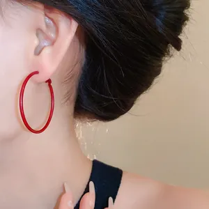 Macro view of large Ancora red hoop earrings worn by a model for fashion detail