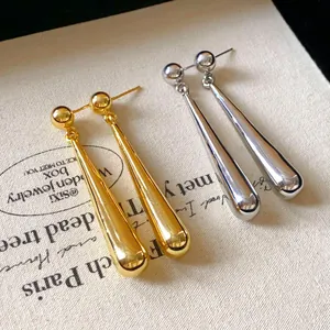 Detailed view of elegant metallic waterdrop long earrings in gold and silver colors