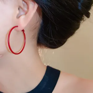 Close-up of Ancora Red hoop earrings worn on ear, showing vibrant color and minimalist design.