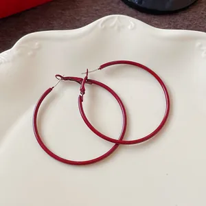 Detailed close-up view of elegant Ankara red large hoop earrings on a white plate