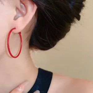 Detailed close-up view of elegant red large hoop earrings worn by an Asian model
