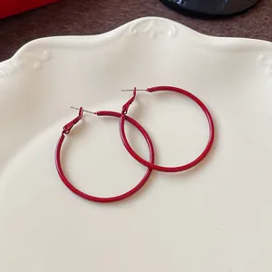 Close-up of elegant Ankara red hoop earrings on a white porcelain plate
