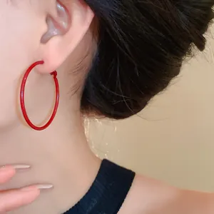 Detailed view of minimalist Ankora red silver needle hoop earrings on an Asian model