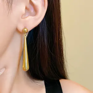 Detail view showing elegant minimalist golden water drop dangle earrings on a model