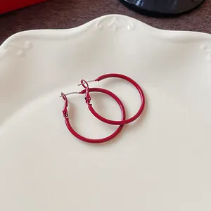 Detailed macro shot of minimalist Ankara red round hoop earrings on a white ceramic plate