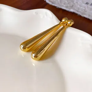Close-up of elegant gold waterdrop long earrings on white ceramic plate