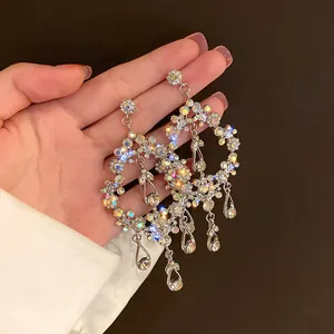 Close-up of elegant floral crystal tassel earrings with AB rhinestones held in hand.