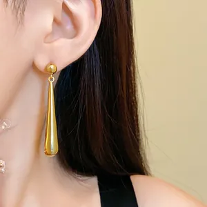 Detailed macro shot of elegant golden teardrop earrings worn by a model in a minimal style