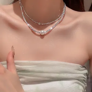 Close-up of elegant double-layered silver geometric necklace with pearls on model neck