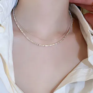 Detailed close-up view showing the texture of geometric silver layered necklaces on model