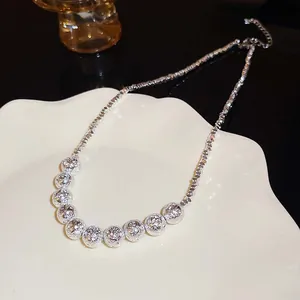 Macro view of minimalist silver necklace with textured geometric beads on a white tray