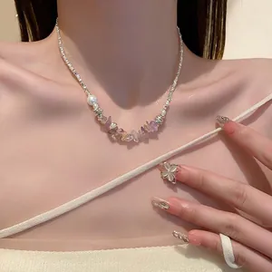 Close-up of minimalist silver necklace with colorful crystals and floral ring on model.