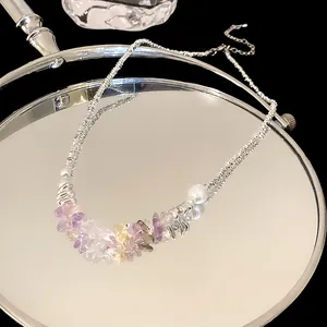 Detail of elegant silver necklace with colorful crushed stones and pearl on mirror.