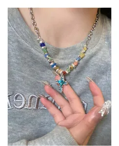 Detailed macro shot of a silver cross necklace featuring colorful beads worn by model