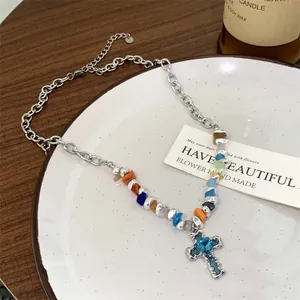 Close-up of silver geometric necklace with colorful beads and blue heart cross pendant