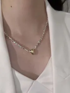Elegant silver geometric choker necklace with a gold heart pendant detail on neck