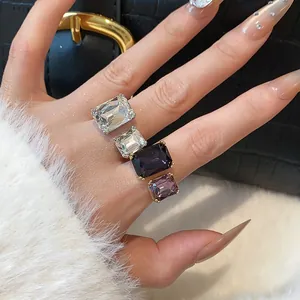 Détail en gros plan de quatre bagues ouvertes élégantes en cristal taillé en carré, tons violets