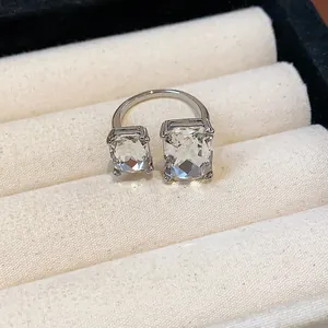 Gros plan d'une bague ouverte en argent avec deux cristaux rectangulaires clairs