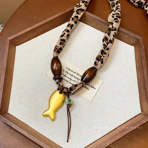 Elegante collana in tessuto leopardato con ciondolo a forma di pesce dorato e perline