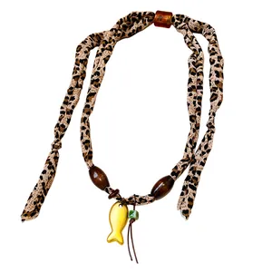 Collana in tessuto leopardato con perle di legno e ciondolo a forma di pesce dorato.